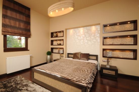 Belles niches en plaques de plâtre avec éclairage décoratif au mur en tête de lit dans la chambre