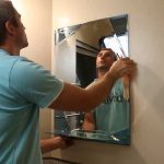 Nous accrochons un miroir dans la photo de la salle de bain