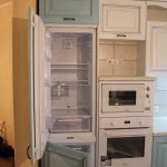 Un réfrigérateur intégré dans le placard et fabriqué dans la même couleur et le même matériau que l'ensemble de la cuisine