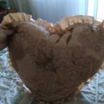 Coussin beige avec des roses et des volants en forme de coeur