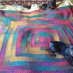 Couverture multicolore sur le lit avec 10 aiguilles en tricot